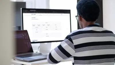 Man sitting in front of a PC screen and looking at an application