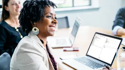 Woman sitting in front of a laptop with application on screen