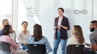 People sit in training and a woman stands in front and presents.