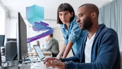 Two women collaborate on a laptop in an office.