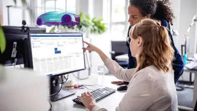 Two female software engineers collaborating on virtualization and automated testing software on a computer in a modern office setting.